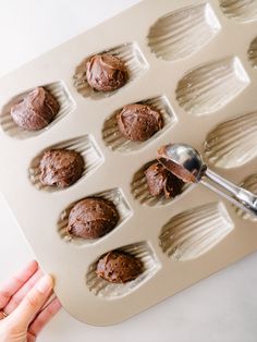 a person scooping chocolate into a muffin pan