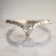 a diamond ring sitting on top of a white cloth covered table next to a light colored wall