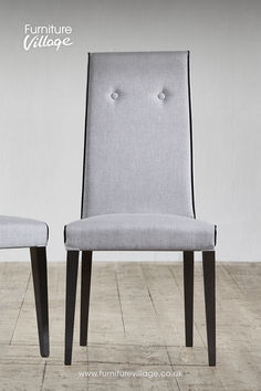 two grey chairs sitting side by side on top of a wooden floor