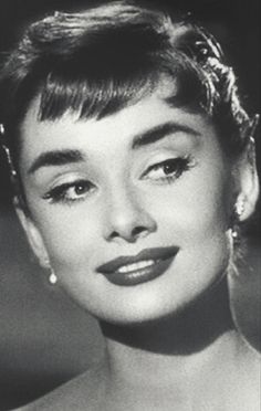 an old black and white photo of a woman with short hair wearing pearls on her head