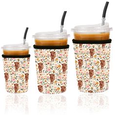 three coffee cups with lids and straws on the top are decorated with floral designs