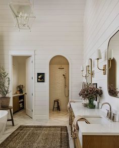 a large bathroom with two sinks and a bathtub in the corner, along with a rug on the floor