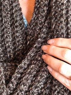 a close up of a person wearing a knitted sweater with their hands on her chest