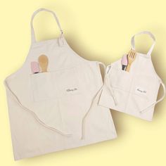 two aprons with wooden utensils in them on a yellow and white background