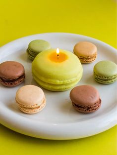 a white plate topped with macaroons and a lit candle