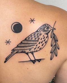 a bird with an olive branch in its beak on the back of a woman's shoulder