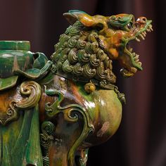 a green and gold statue with a dragon on it's back end, sitting in front of a black background