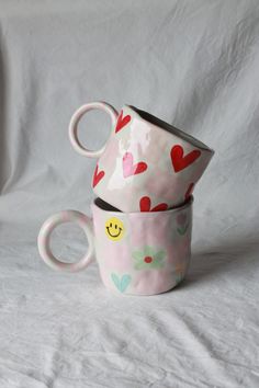 three coffee cups with hearts on them sitting next to each other in front of a white background