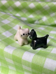 two small black and white dog figurines on a green checkered cloth