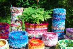 colorful crocheted baskets and planters sitting on the ground