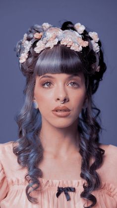 a woman with long dark hair wearing a flowered headpiece and pink dress, posing for the camera