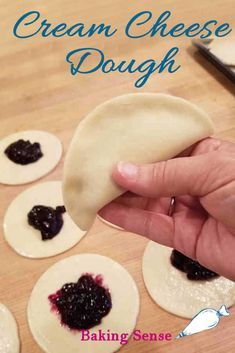 a hand is holding a pastry with blueberry sauce on it and the words cream cheese dough