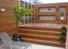 a hot tub sitting on top of a wooden deck next to a potted plant