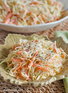 two bowls filled with coleslaw and carrots on top of a woven table cloth