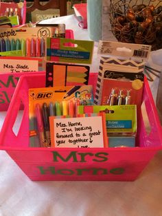 two pink baskets filled with school supplies on top of a table