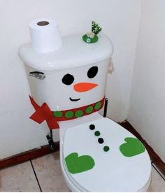 a toilet decorated like a snowman sitting in a bathroom next to a roll of toilet paper