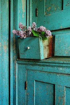 an old blue cabinet with some flowers in it