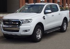 a white pickup truck parked in front of a building with red brick walls and doors