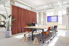 a conference room with orange chairs and a flat screen tv