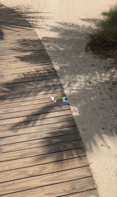 a wooden walkway leading to the beach with two bottles on it and one empty bottle in the sand