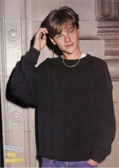 a young man is talking on his cell phone while standing in front of a door