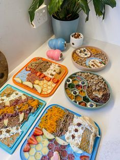 several trays filled with food sitting on top of a table next to a potted plant