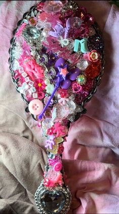 a heart shaped brooch laying on top of a pink blanket