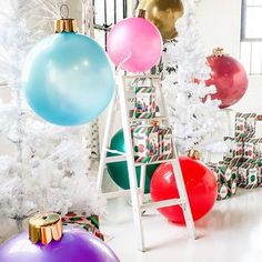 colorful balloons and presents are on display in front of a white christmas tree