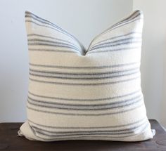 a white and blue striped pillow sitting on top of a wooden table