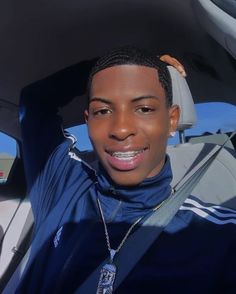 a young man sitting in the back seat of a car with his hand up to his head