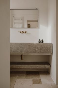 a bathroom sink with a mirror above it and two vases on the counter next to it