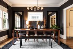 the dining room table is surrounded by black walls and wooden flooring, along with an area rug