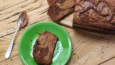 a loaf of bread sitting on top of a green plate next to a knife and fork