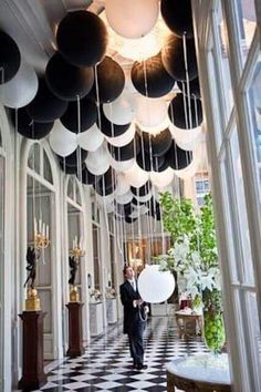 an image of a man standing in the middle of a room with black and white balloons