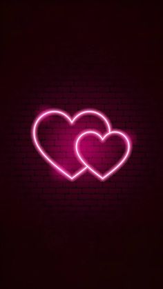 two neon hearts against a brick wall