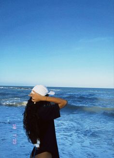 a woman standing on top of a beach next to the ocean