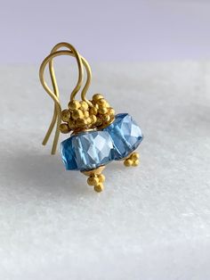 "22k Gold London Blue Topaz Earrings. Using the ancient technique of Gold granulation I've created 22k solid Gold beads. Placing them in an organic cascade atop these stunning faceted London Blue Topaz cube gemstones has resulted in a beautiful harmony of elements. Slightly over 1\" long my \"Golden Bubble\" earrings add an elegant touch while caressing the face and dangling from the French style 18k Gold ear wires." Handmade Gold Earrings With Blue Topaz, London Blue Topaz Earrings, Bubble Earrings, Blue Topaz Earrings, Topaz Earrings, London Blue Topaz, London Blue, 22k Gold, French Style