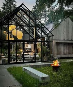 a glass house with a fire pit in the front yard and lawn area next to it