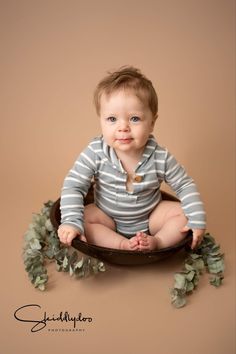 a baby sitting in a bowl with greenery