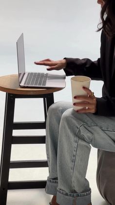 a woman sitting at a table with a coffee cup and laptop