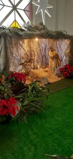 christmas decorations in the shape of nativity scene displayed on fake grass with red poinsettias