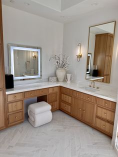 a large bathroom with wooden cabinets and marble counter tops, along with a white foot stool