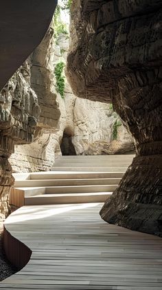 a wooden walkway between two large rocks with steps leading up to it and another stone structure in the background