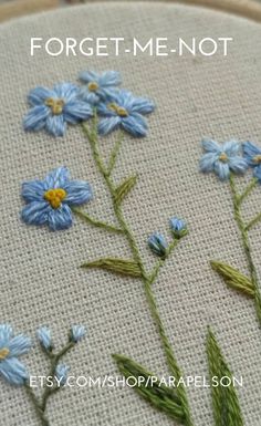 some blue flowers are sitting on a white piece of fabric with the words forget me not