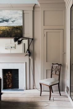 a room with a chair, fireplace and painting on the wall