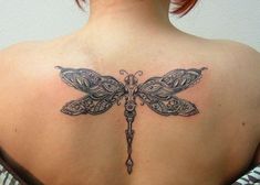 the back of a woman's shoulder with a dragonfly tattoo on her upper