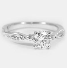 a white gold engagement ring with a twisted band and a round diamond center stone in the middle