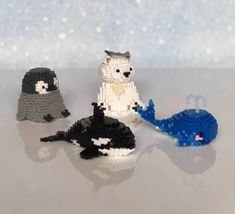 three small knitted animals sitting next to each other on top of a table with snow in the background