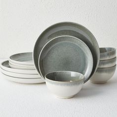 a stack of white and gray dishes on top of each other in front of a white wall