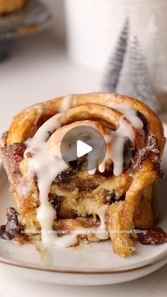 a cinnamon roll on a plate with icing drizzled over the top